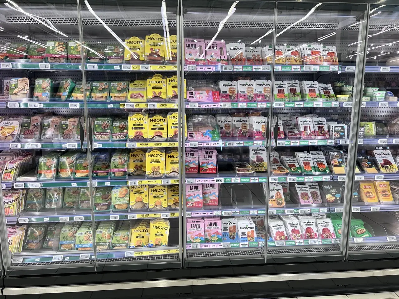 Rayon réfrigéré d'un supermarché avec divers produits végétariens et véganes emballés, notamment Heura, HappyVore et Garden Gourmet.